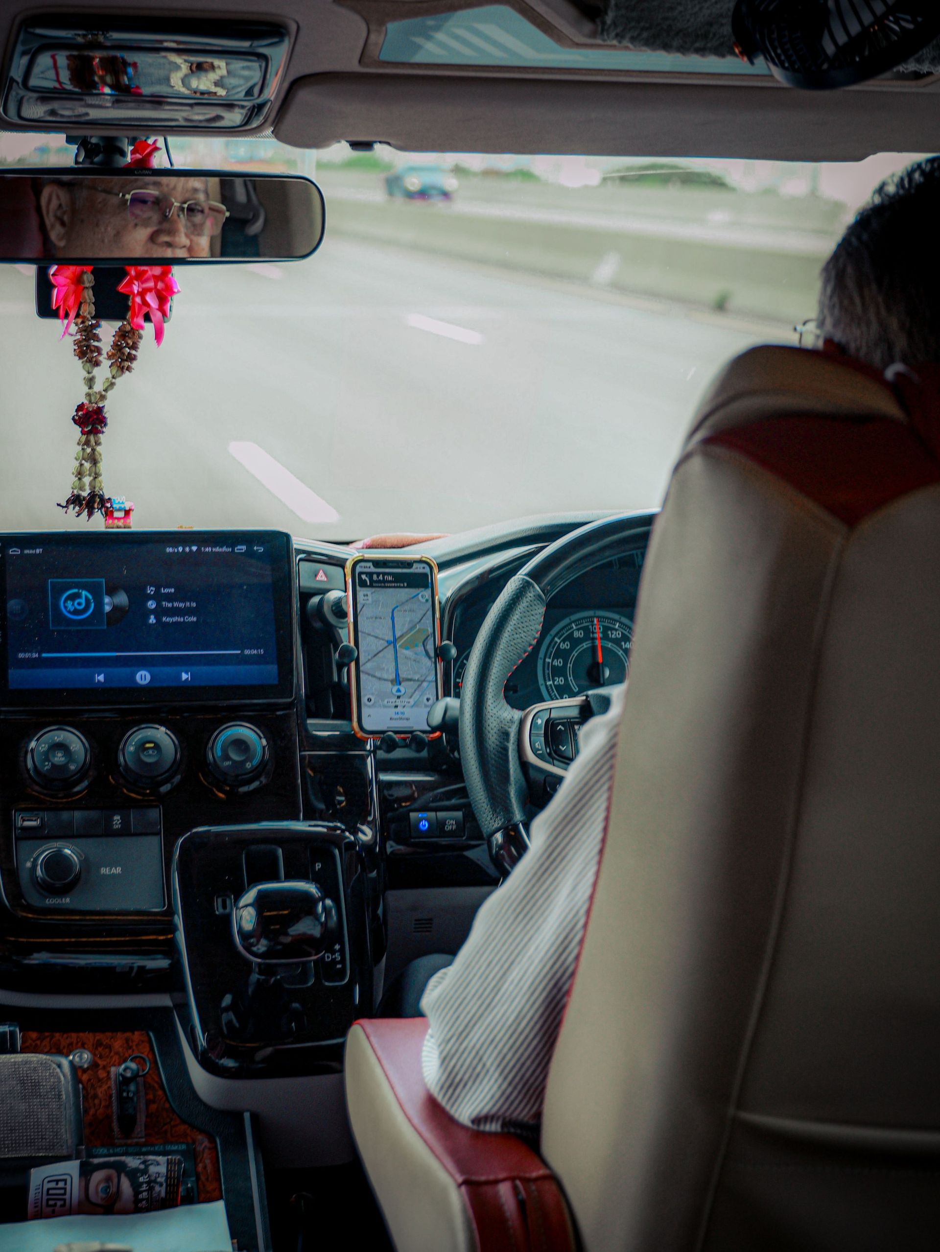 View inside a moving vehicle in Bangkok, highlighting dashboard technology and city travel vibes.