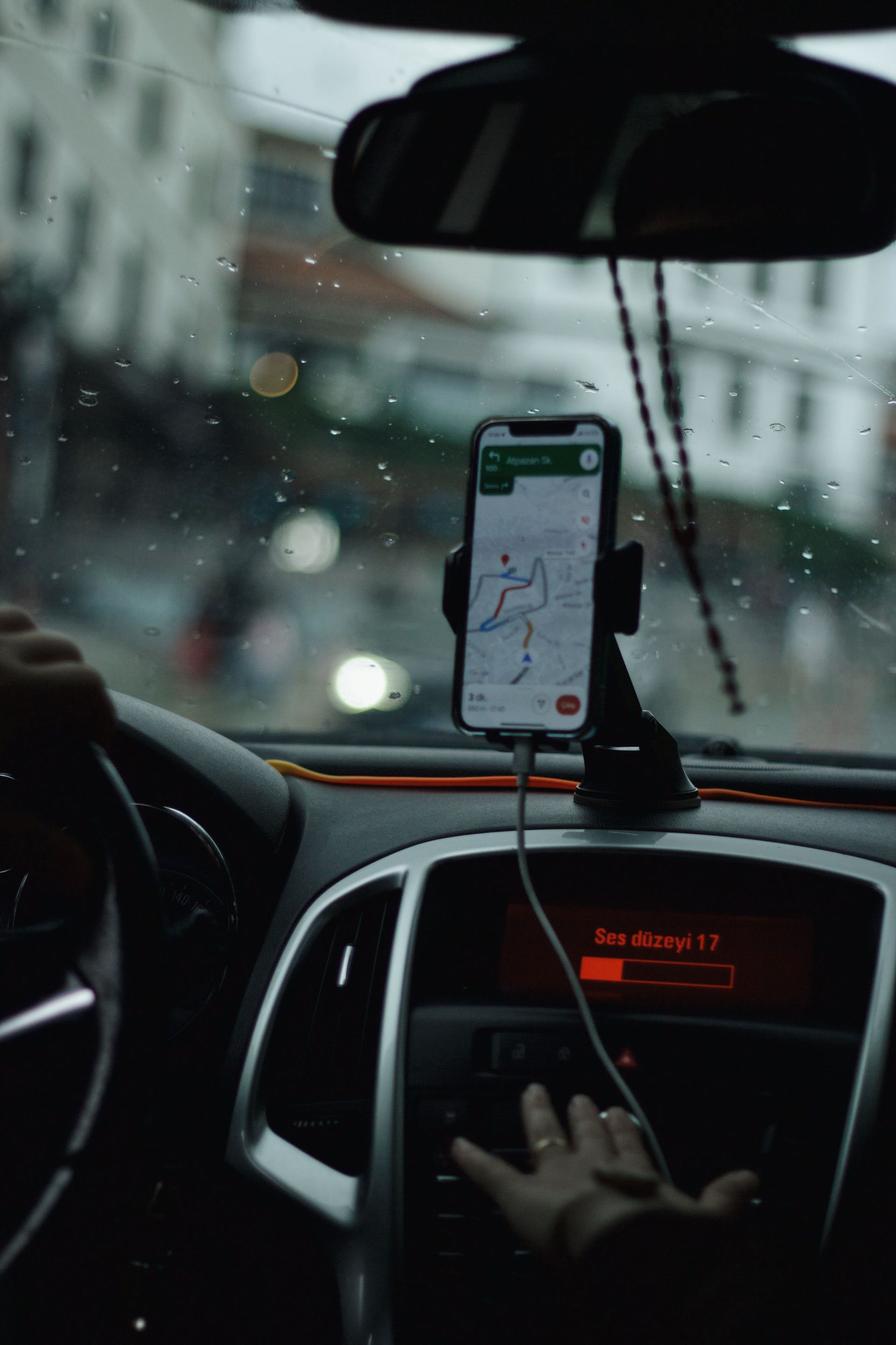 View of a car interior focusing on GPS navigation with raindrops on windshield.