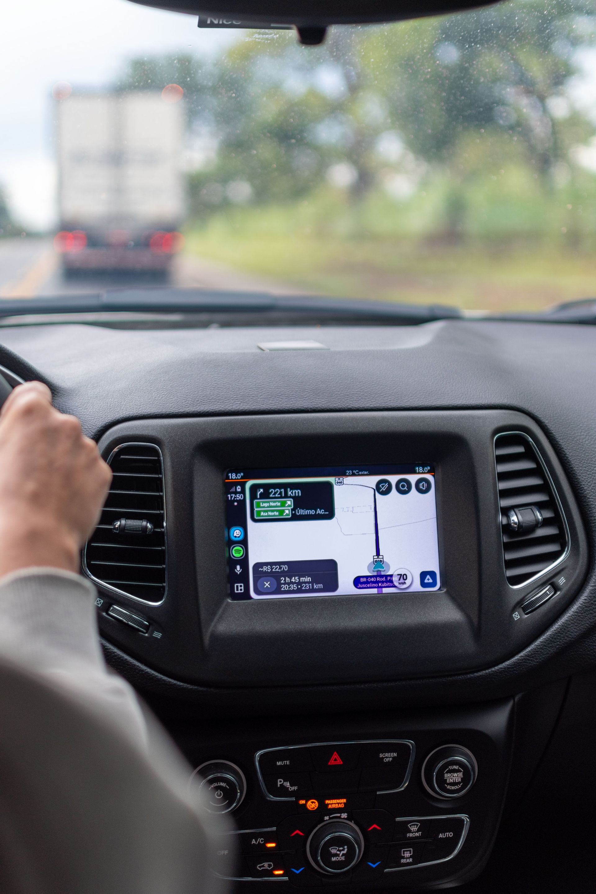 View of GPS navigation screen inside a moving car with driver on the road.